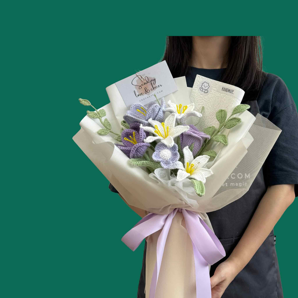 Bouquet of flowers with a card held by a person against a green background